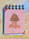 Notebook with a cartoon poop emoji and 'I'll Forget' text on a wooden surface