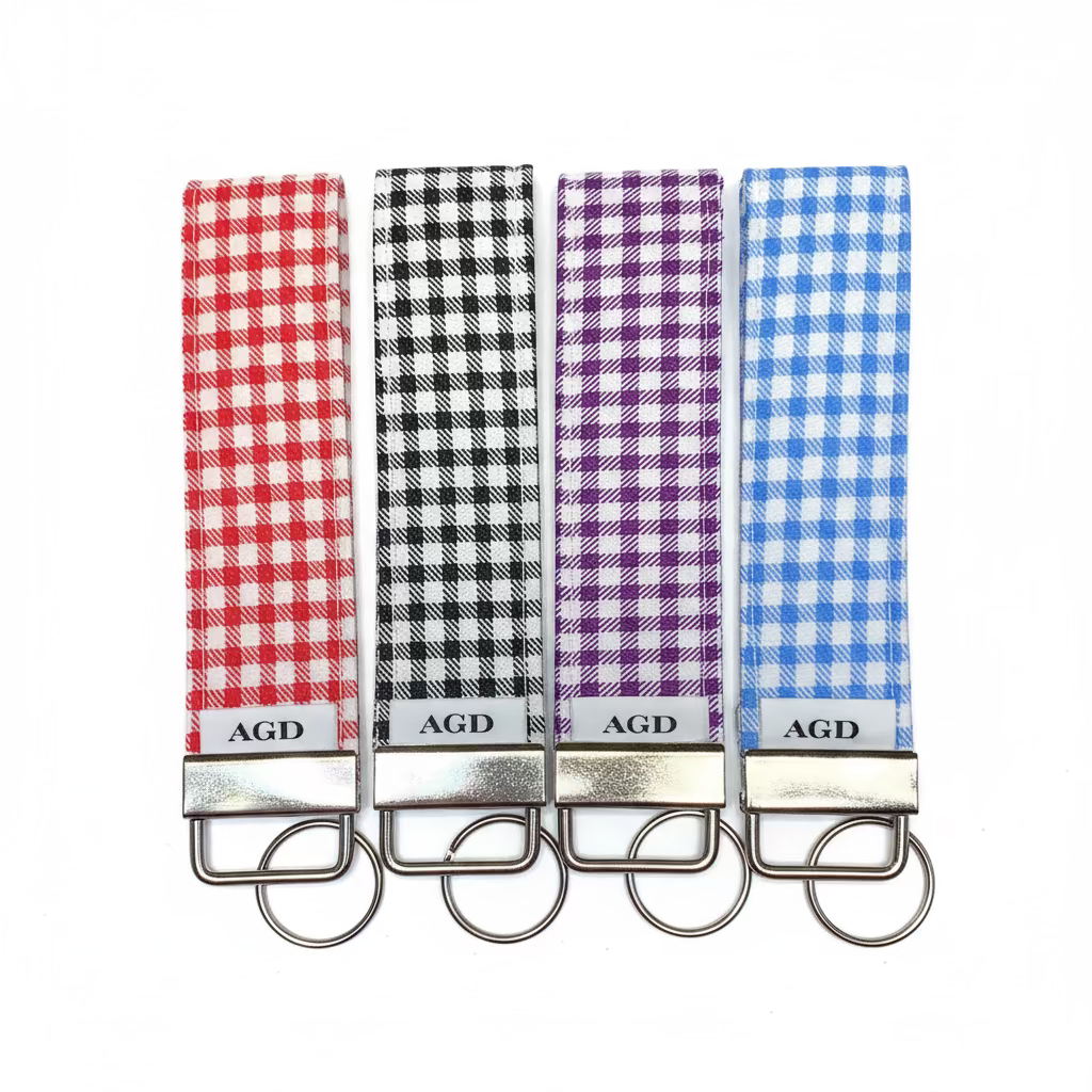 Four plaid keychains with 'AGD' branding on a woven surface.