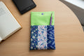 Floral patterned pouch with a green flap on a white background