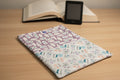 Two patterned fabric swatches, one with bottle illustrations on a purple background and the other with floral and text design on a white background.