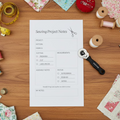 Sewing project notes sheet with a rotary cutter on a gray background