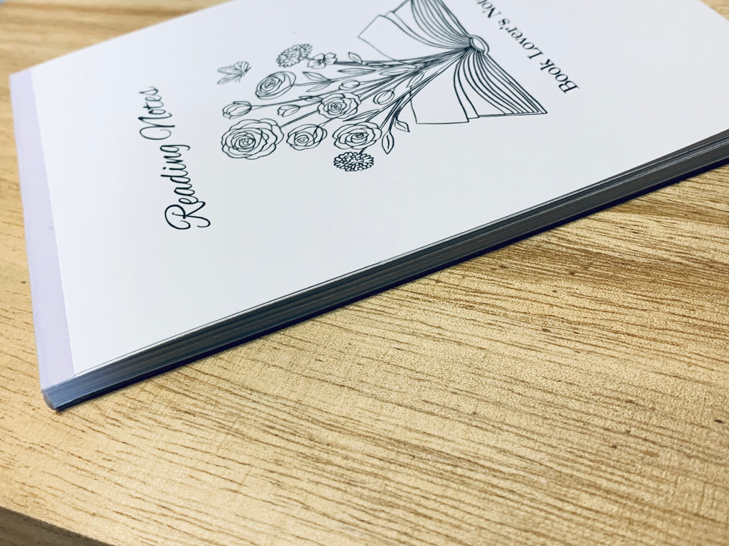 Notebook with floral design and text on a wooden surface