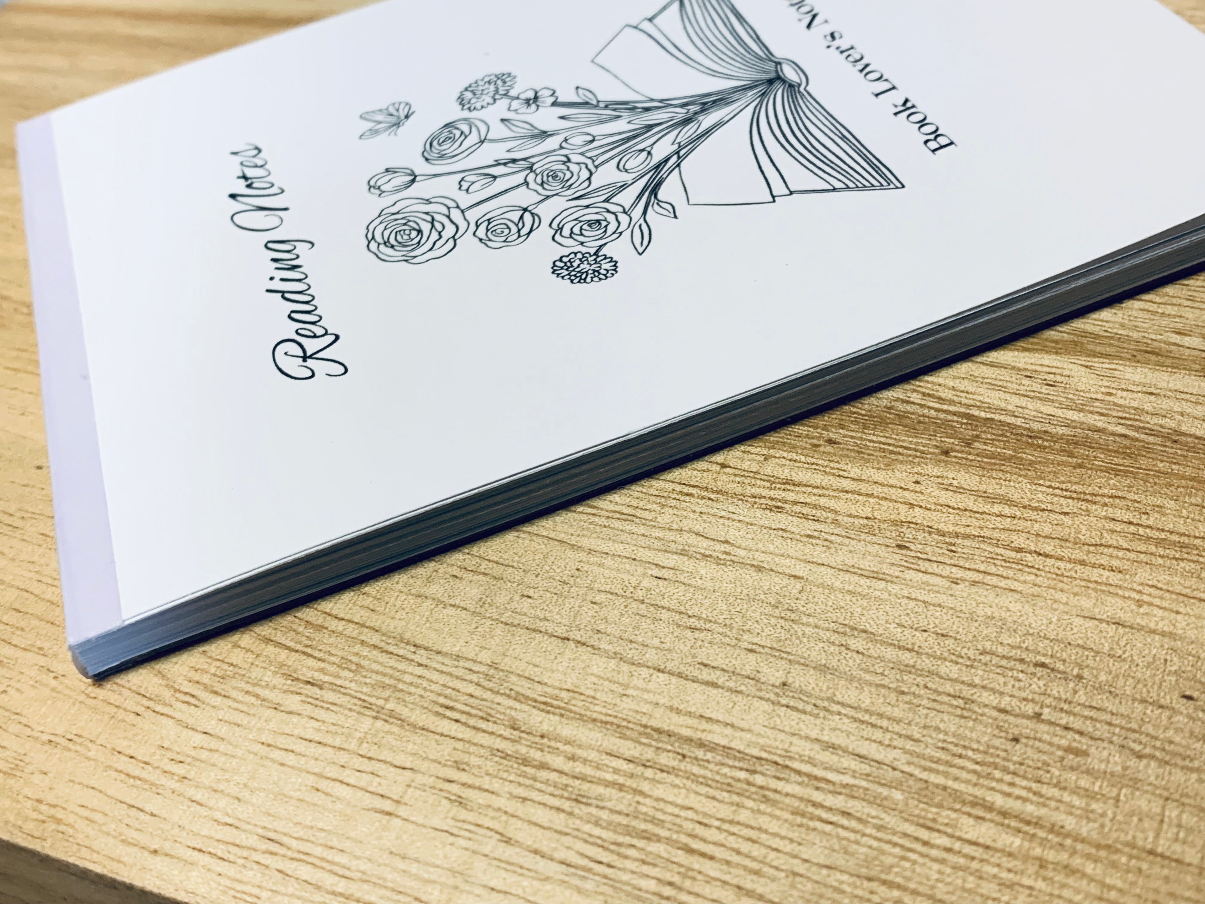 Notebook with floral design and text on a wooden surface