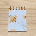 Small notebook with bee illustrations on a wooden surface
