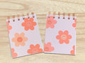 Two small notebooks with floral designs on a wooden surface