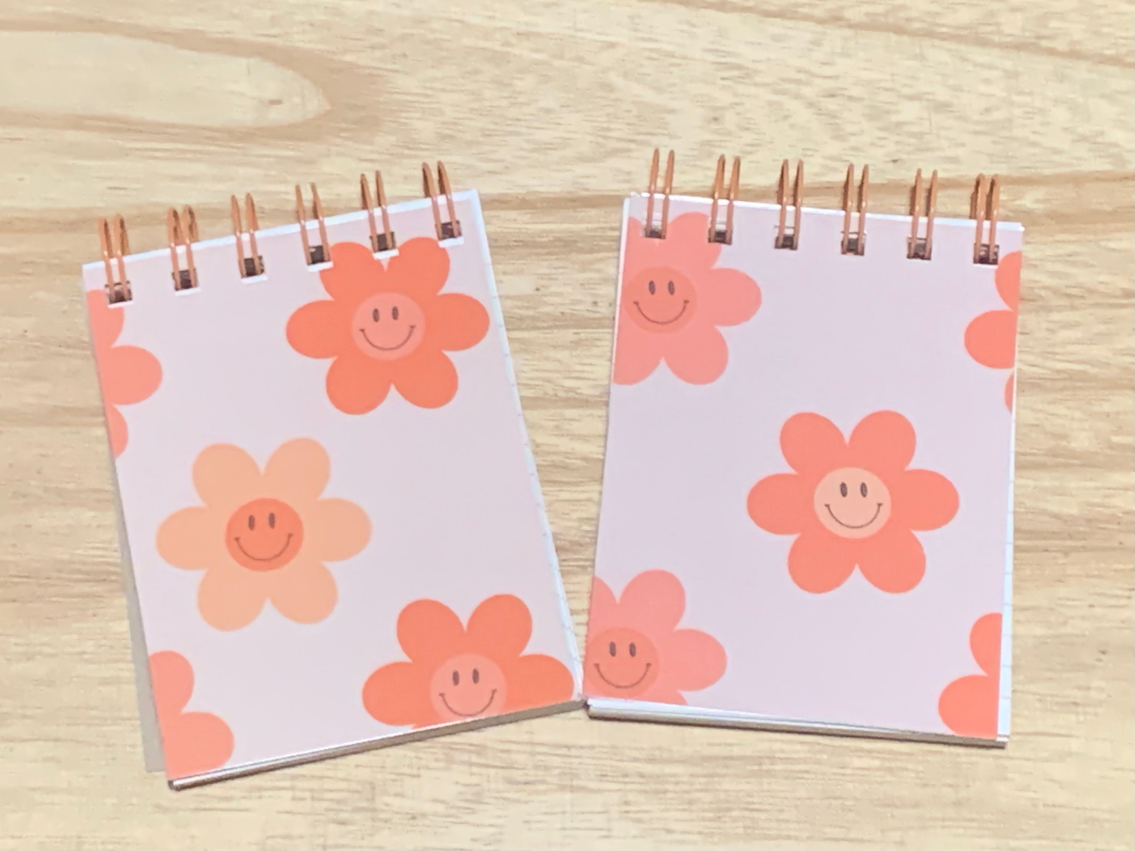 Two small notebooks with floral designs on a wooden surface