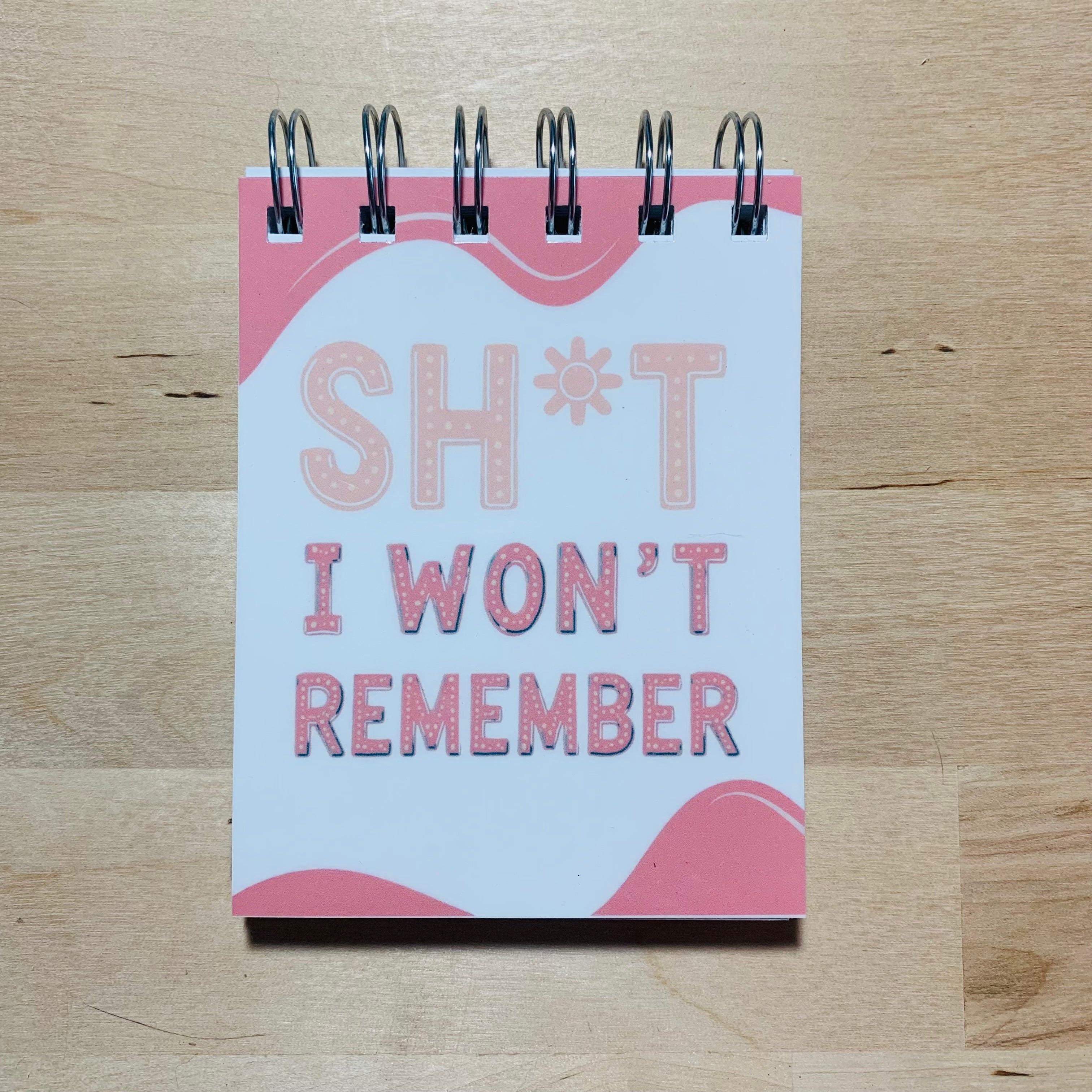 Notebook with 'Sh*t I Won't Remember' text on a wooden surface
