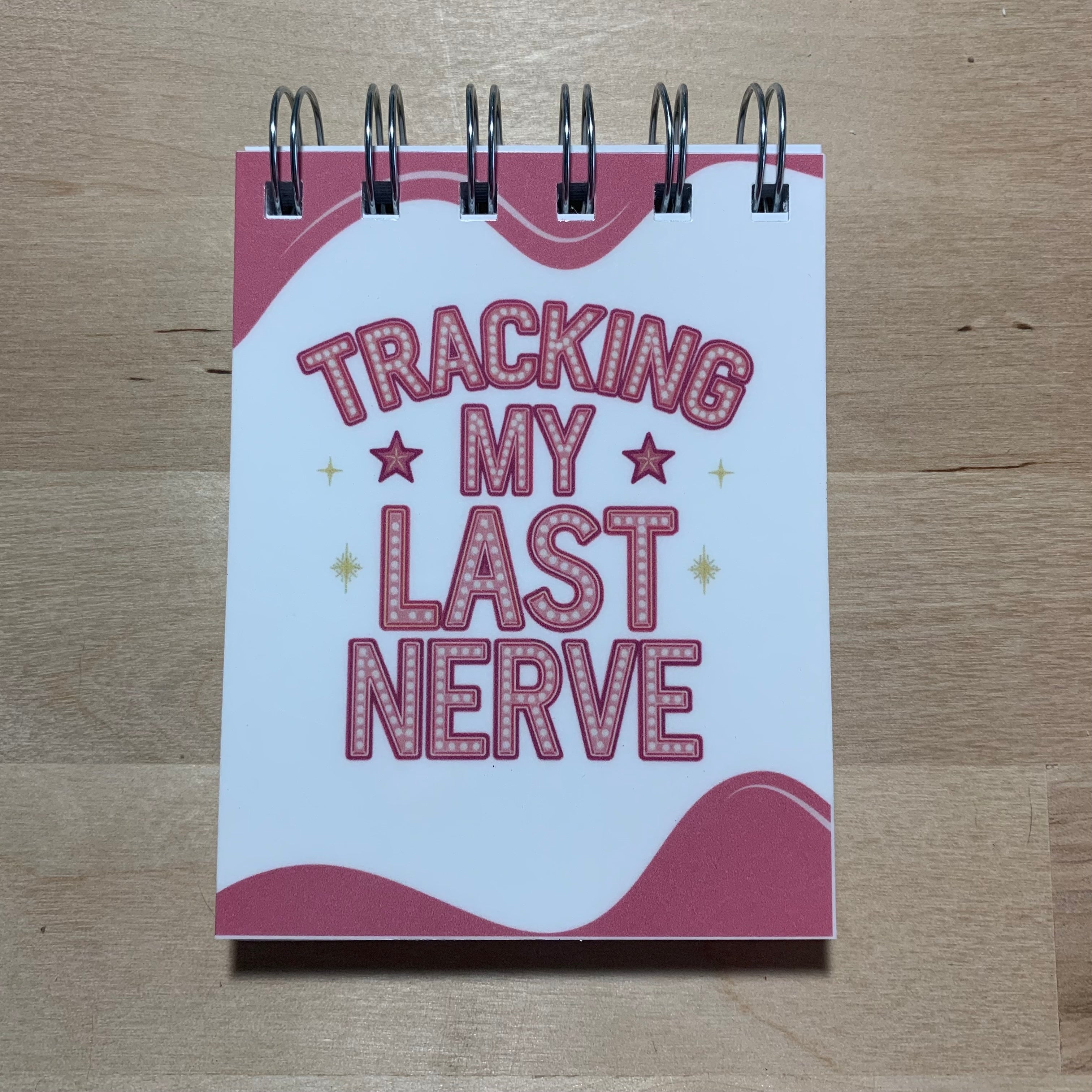 Small notebook with 'Tracking My Last Nerve' text on a wooden surface