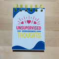 Notebook with 'Unsupervised Thoughts' on a wooden surface