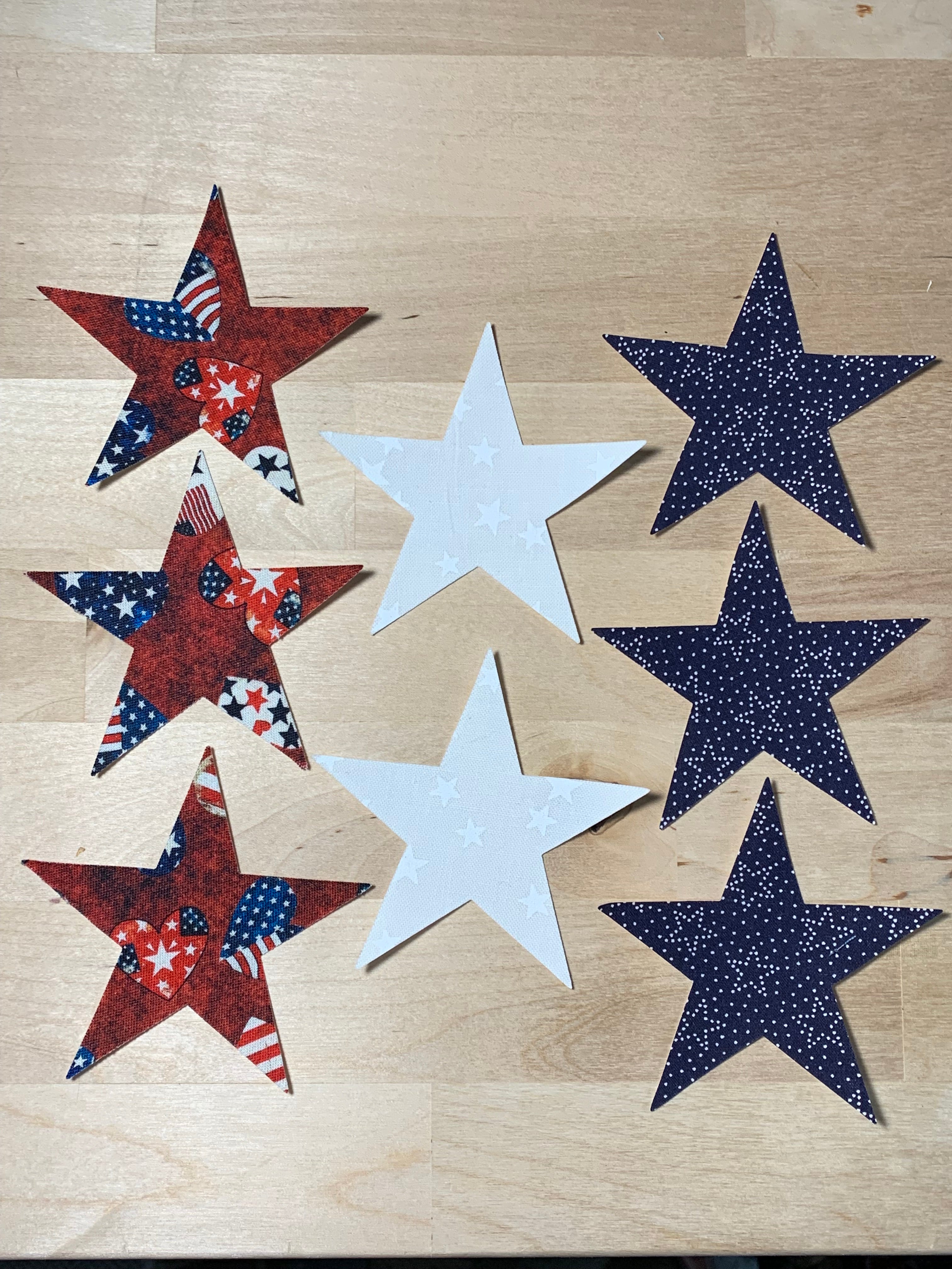 Star-shaped fabric pieces in blue, white, and red on a wooden surface