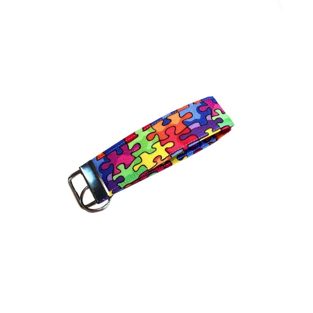 Colorful puzzle patterned strap on a wooden surface with pink flowers